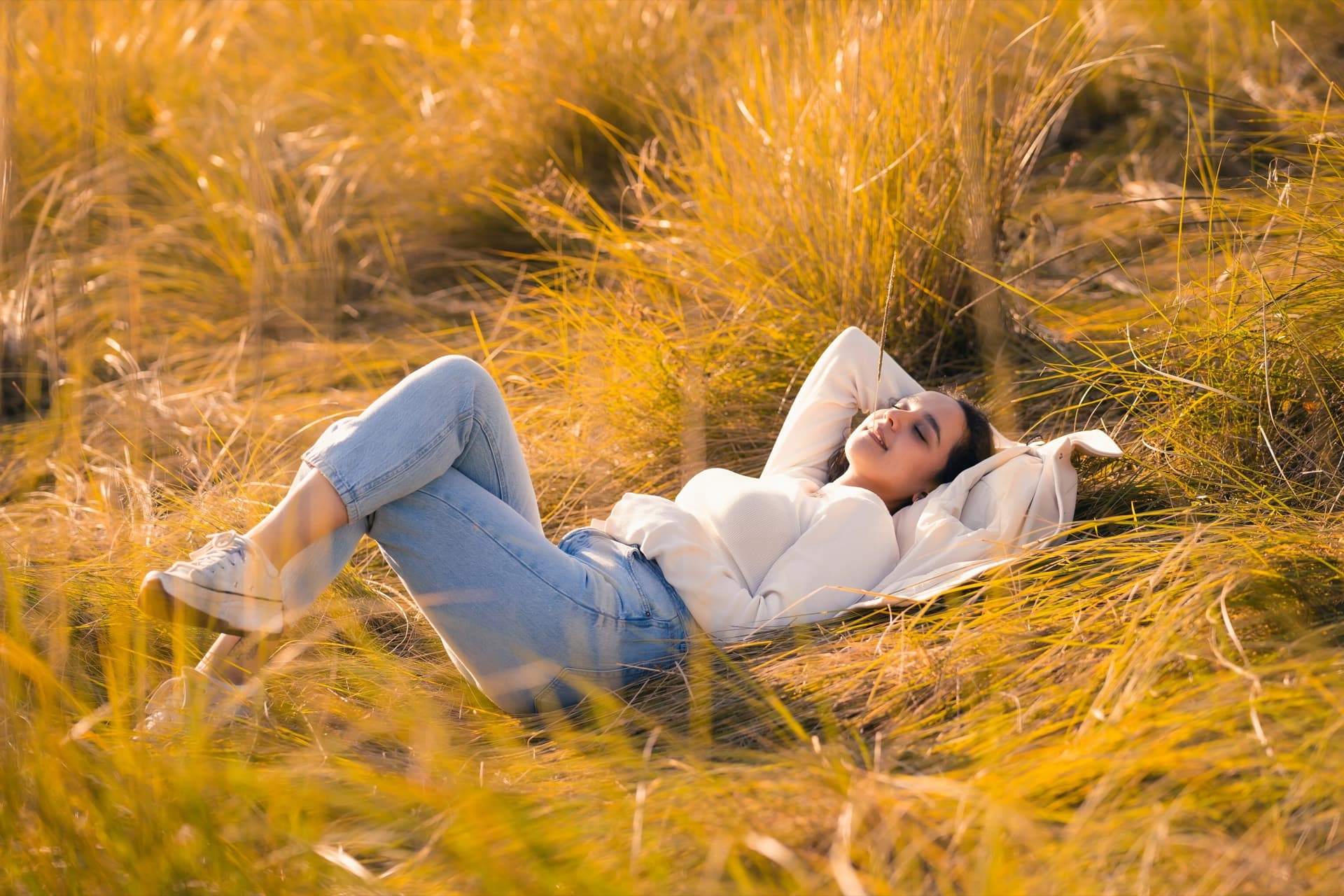 Gabriele, somatic and intimacy coach, sitting on the grass in a relaxed, welcoming pose